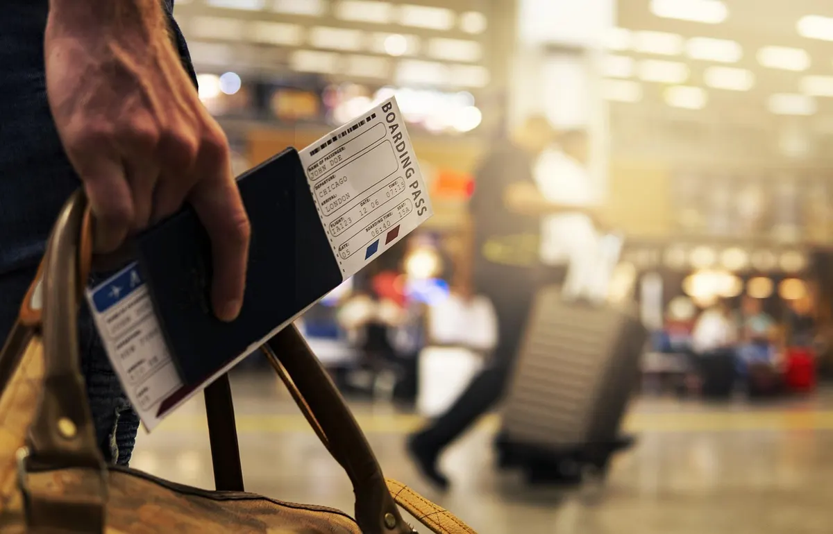 Auswanderer mit Reisepass, Boarding-Pass und Koffer am Flughafen beim Auswandern ins Ausland